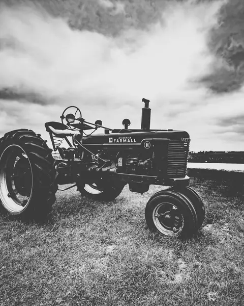 Gammal traktor i svartvitt på en äng